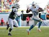 Running back Lamar Miller #26 of the Miami Dolphins tries to elude cornerback Marcus Williams #22 of the New York Jets in the second quarter during a game at Sun Life Stadium on December 28, 2014