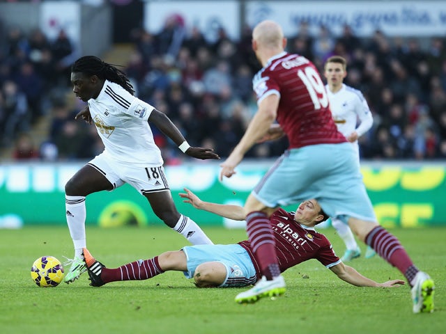 Bafetibis Gomis of Swansea City is tackled by Mark Noble of West Ham United during the Barclays Premier League match between Swansea City and West Ham United at Liberty Stadium on January 10, 2015