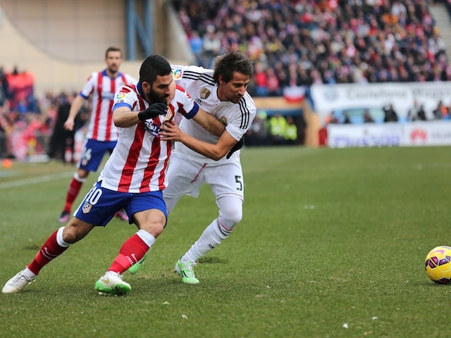 Atletico Madrid's Turkish midfielder Arda Turan (L) vies with Real Madrid's Portuguese defender Fabio Coentrao during the Spanish league football match on February 7, 2015