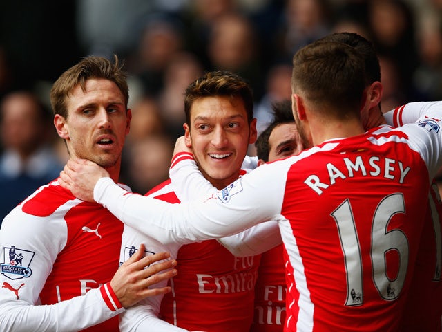 Mesut Ozil of Arsenal celebrates scoring the opening goal with team mates during the Barclays Premier League match between Tottenham Hotspur and Arsenal at White Hart Lane on February 7, 2015