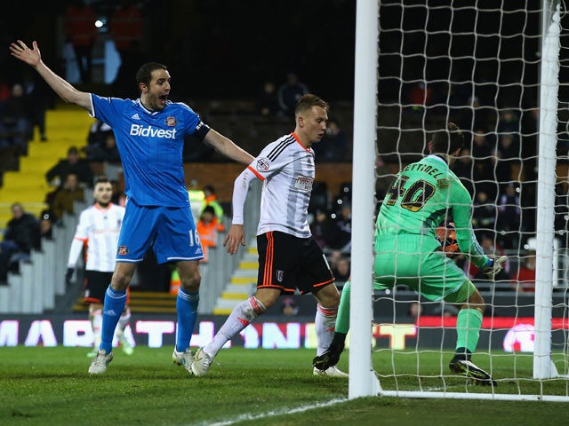 Marcus Bettinelli of Fulham fumbles the ball in to his own net for Sunderland's opening goal as John O'Shea of Sunderland celebrates during the FA Cup Fourth Round Replay match between Fulham and Sunderland at Craven Cottage on February 3, 2015