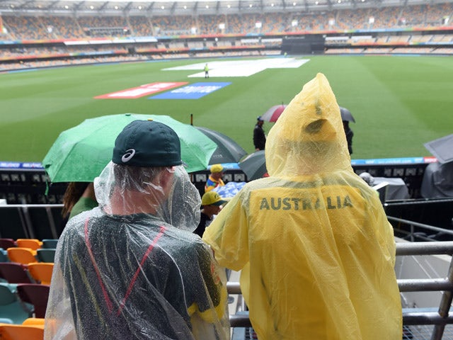 Spectators wearing rain gear wait in the stands as rain from Cyclone Marcia delays the start of the 2015 Cricket World Cup match between Australia and Bangladesh at the Gabba cricket stadium in Brisbane on February 21, 2015