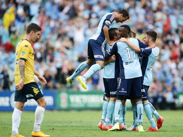 Rhyan Grant of Sydney FC celebrates with team mates after scoring a goal as Alex Brosque of Sydney FC jumps over the top during the round 18 A-League match between Sydney FC and the Central Coast Mariners at Allianz Stadium on February 21, 2015