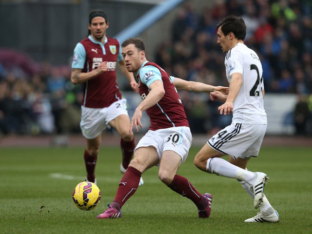 Ashley Barnes of Burnley clears the ball as Jack Cork of Swansea City closes in during the Barclays Premier League match between Burnley and Swansea City at Turf Moor on February 28, 2015 