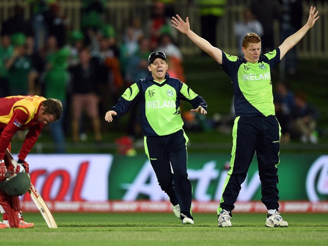 Ireland cricketer Nial O'Brien runs in to congratulate brother and teammate Kevin O'Brien after he took the wicket of Zimbabwe batsman Sean Williams (L) at the Bellerive Oval ground during the 2015 Cricket World Cup Pool B match between Ireland and Zimbab