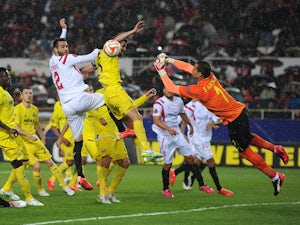 Sergio Asenjo of Villarreal fists the ball away from Vicente Iborra of FC Sevilla during the UEFA Europa League Round of 16, Second Leg match between FC Sevilla and Villarreal CF at Estadio Ramon Sanchez Pizjuan on March 19, 2015