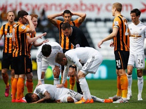 Referee Andre Marriner checks on Kyle Naughton of Swansea City after showing the red card to David Meyler of Hull City during the Barclays Premier League match between Swansea City and Hull City at Liberty Stadium on April 4, 2015