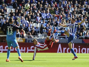 Atletico Madrid's French forward Antoine Griezmann kicks the ball over Deportivo's goalkeeper Fabri (L) and forward Toche to score a goal during the Spanish league football match RC Deportivo La Coruna v Club Atletico de Madrid at the Municipal de Riazor 