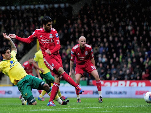 Luis Suarez of Liverpool takes a shot on goal as Bradley Johnson of Norwich slides in during the Barclays Premier League match between Norwich City and Liverpool at Carrow Road on April 28, 2012