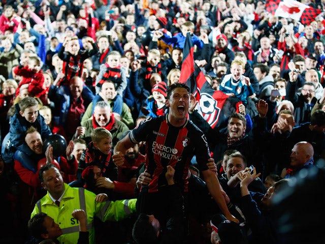 Captain Tommy Elphick of Bournemouth celebrates victory as fans invade the pitch after the Sky Bet Championship match between AFC Bournemouth and Bolton Wanderers at Goldsands Stadium on April 27, 2015