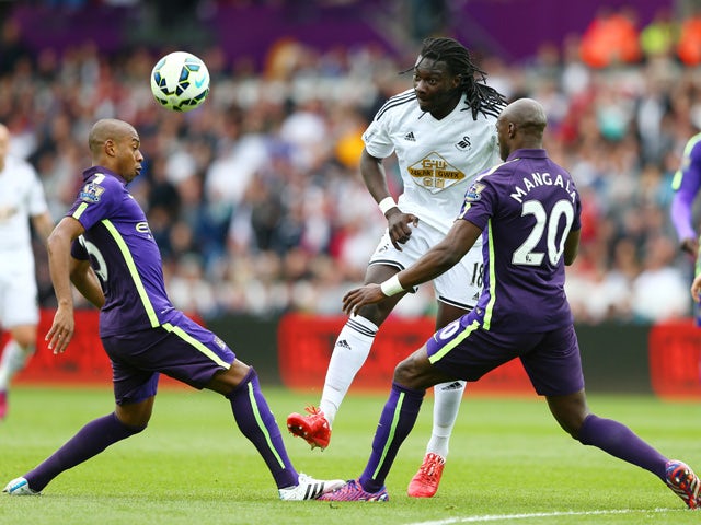 Bafetibis Gomis of Swansea City is closed down by Fernandinho of Manchester City and Eliaquim Mangala of Manchester City during the Barclays Premier League match between Swansea and Manchester City at the Liberty Stadium on May 17, 2015