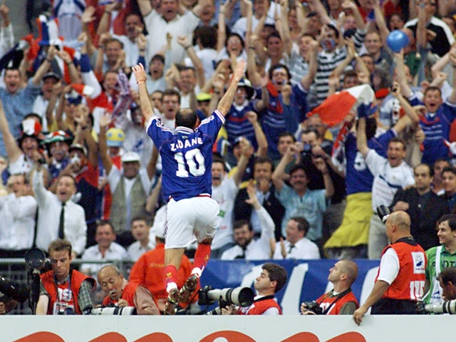 French Zinedine Zidane jumps over the barrier as he celebrates after scoring the first goal for his team 12 July outside the Stade de France in Saint-Denis, during the 1998 World Cup final match between Brazil and France