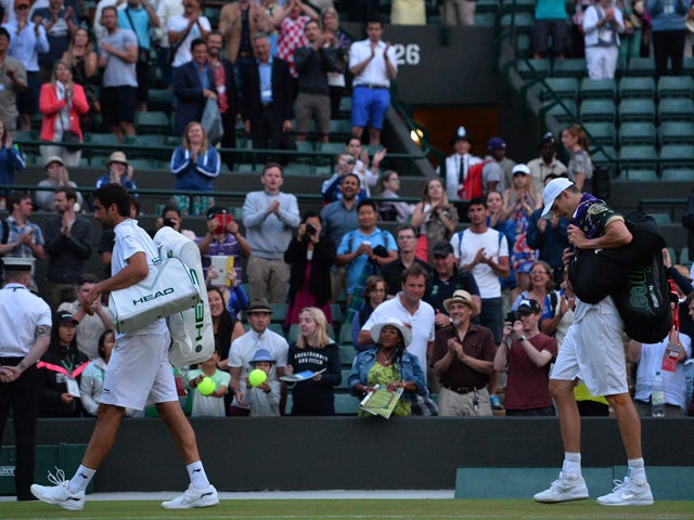 Croatia's Marin Cilic (L) and US player John Isner leave the court after match was postponed due to low light, during their men's singles third round match on day five of the 2015 Wimbledon Championships at The All England Tennis Club in Wimbledon, southw