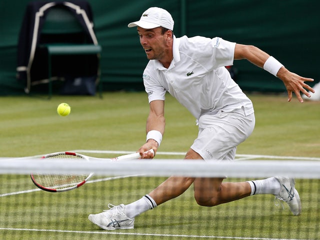 Spain's Roberto Bautista Agut strines his knee as he stretches to return to France's Benoit Paire during their men's singles second round match on day four of the 2015 Wimbledon Championships at The All England Tennis Club in Wimbledon, southwest London, 