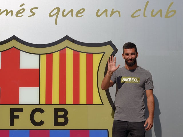Barcelona's new player Turkish Arda Turan waves as he poses outside the Camp Nou stadium in Barcelona, prior to signing his new contract with the Catalan club, on July 9, 2015