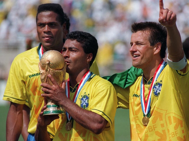 Brazilian forward Romario kisses the FIFA World Cup trophy, flanked by Ronaldao (L) and captain Dunga, after Brazil defeated Italy 3-2 in the shoot-out session (0-0 after extra time) at the end of the World Cup final, 17 July 1994