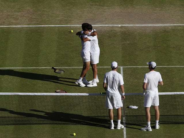 Netherlands' Jean-Julien Rojer (L) and Romania's Horia Tecau (2L) embrace after beating Britain's Jamie Murray (R) and Australia's John Peers (2R) in the men's doubles final on day twelve of the 2015 Wimbledon Championships at The All England Tennis Club 