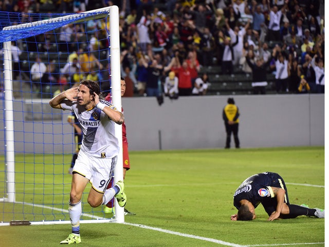 Alan Gordon of the LA Galaxy celebrates after scoring the game-winning goal before the dejected Club America defender Paolo Goltz (R) on July 11, 2015