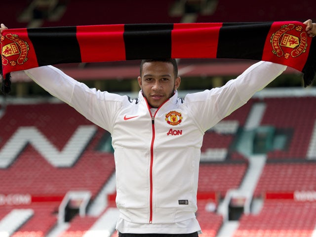 Dutch midfielder Memphis Depay poses with a scarf for a photograph as he is officially unveiled as a Manchester United player at Old Trafford stadium in Manchester, north west England on July 10, 2015