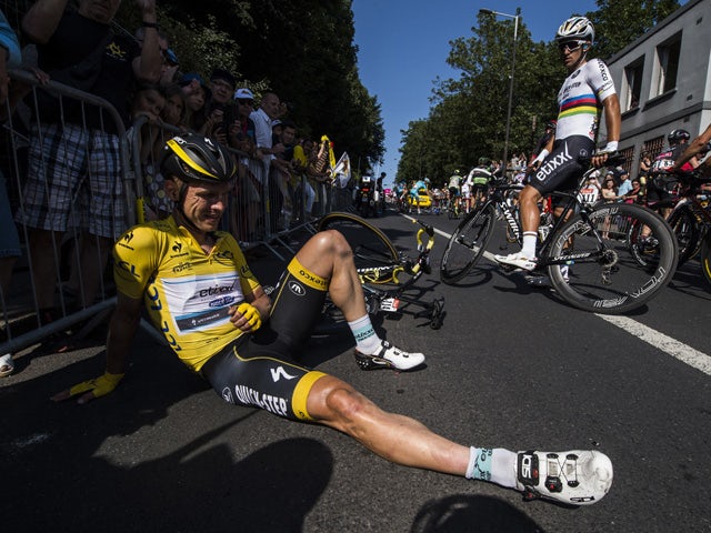 Germany's Tony Martin, wearing the overall leader's yellow jersey, sits on the ground after a fall as Poland's Michal Kwiatkowski looks at him (R), during the 191.5 km sixth stage of the 102nd edition of the Tour de France cycling race on July 9, 2015