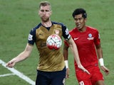 Per Mertesacker of Arsenal is checked by Khairul Amri of Singapore during the Barclays Asia Trophy match between Arsenal and Singapore at National Stadium on July 15, 2015