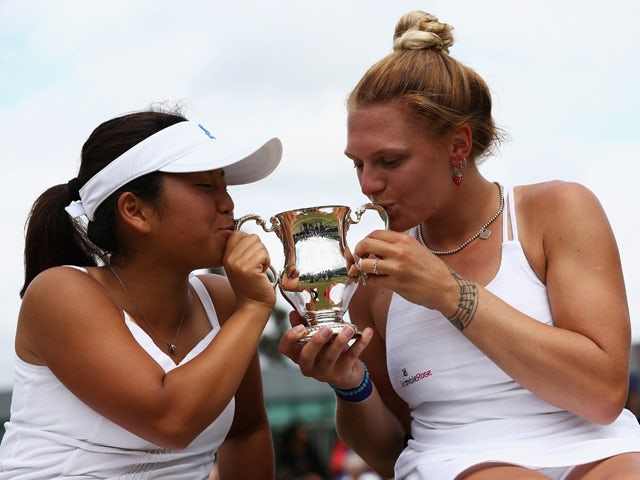 Yui Kamiji of Japan and Jordanne Whiley of Great Britain pose with the trophy after winning the Wheelchair Ladies Doubles Final against Jiske Griffioen and Aniek Van Koot of the Netherlands during day thirteen of the Wimbledon Lawn Tennis Championships at