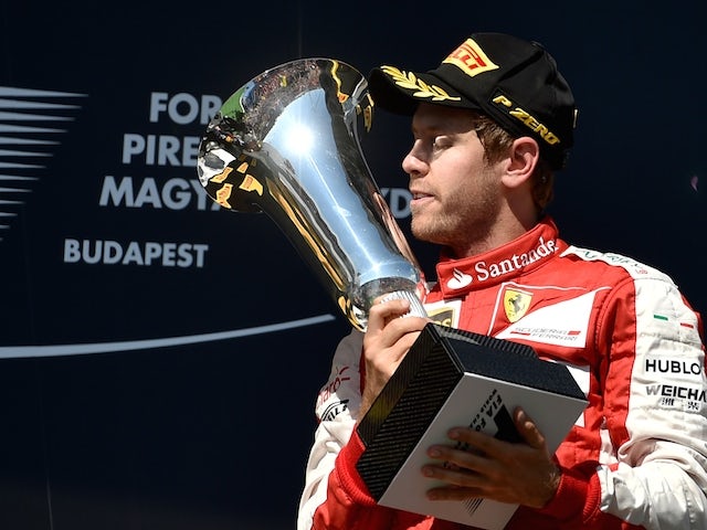 Ferrari's German driver Sebastian Vettel is to kiss the trophy as he celebrates on the podium winning the Hungarian Formula One Grand Prix at the Hungaroring circuit near Budapest on July 26, 2015