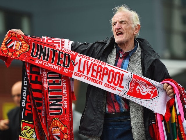 An elderly gentleman flogs two scarves for a tenner outside Old Trafford ahead of the game between Manchester United and Liverpool on September 12, 2015