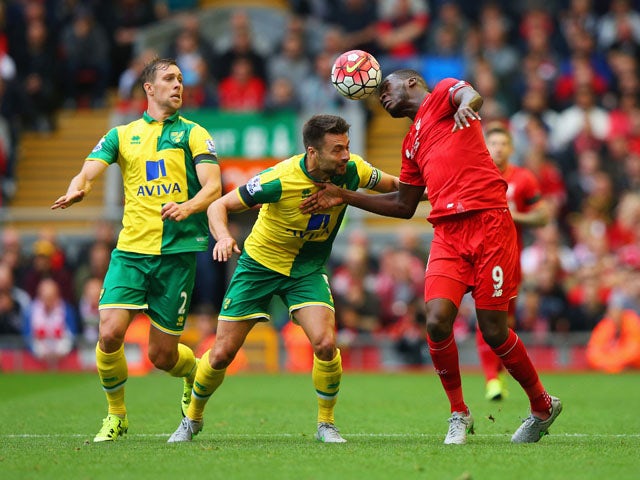 Christian Benteke of Liverpool heads the ball under pressure from Steven Whittaker (L) and Russell Martin of Norwich City during the Barclays Premier League match between Liverpool and Norwich City at Anfield on September 20, 2015