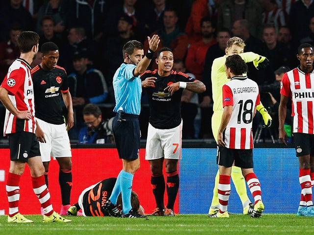 Luke Shaw of Manchester United lies on the ground injured as referee Nicola Rizzoli calls for medical assistance during the UEFA Champions League Group B match between PSV Eindhoven and Manchester United at PSV Stadion on September 15, 2015