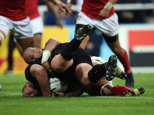 New Zealand's prop Tony Woodcock (down) scores his team's second try despite a tackle by Tonga's flanker and captain Nili Latu (up) during a Pool C match of the 2015 Rugby World Cup between New Zealand and Tonga at St James' Park in Newcastle-upon-Tyne, n