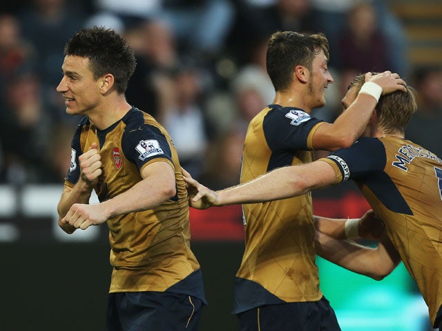 Laurent Koscielny (L) of Arsenal celebrates scoring his team's second goal with his team mates Mesut Ozil (C) and Per Mertesacker (R) during the Barclays Premier League match between Swansea City and Arsenal at Liberty Stadium on October 31, 2015