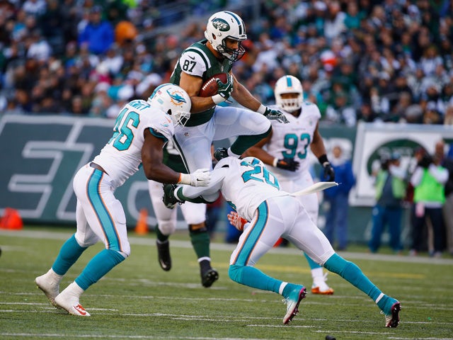 Eric Decker #87 of the New York Jets makes a catch against Reshad Jones #20, and Neville Hewitt #46 of the Miami Dolphins in the second quarter during their game at MetLife Stadium on November 29, 2015