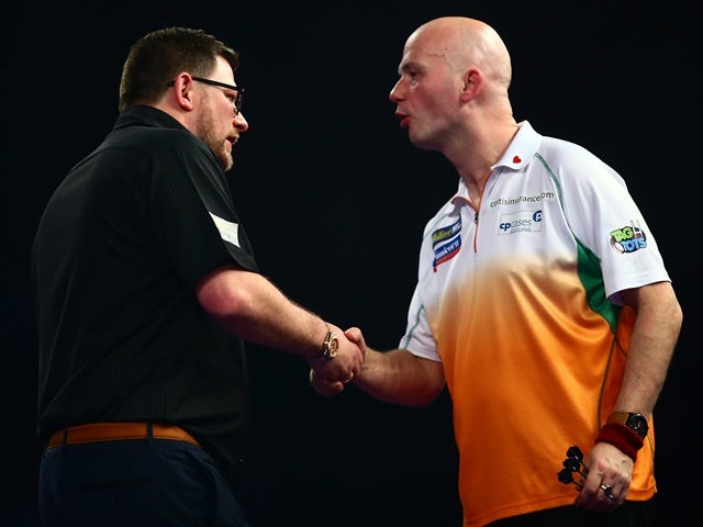 James Wade shakes hands with Jamie Caven after beating him in a game of darts on December 29, 2015
