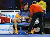 Milos Raonic spreads his legs to receive medical treatment at the Australian Open on January 29, 2016