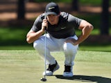 Rory McIlroy squats to line up a shot during the first round of The Masters on April 7, 2016
