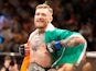 Conor McGregor celebrates winning a fight with his Irish flag and belt