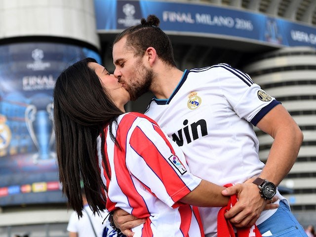 A heterosexual embrace between fans of rival sides, a modern-day depiction of Romeo and Juliet, occurs prior to the Champions League final between Real Madrid and Atletico Madrid on May 28, 2016