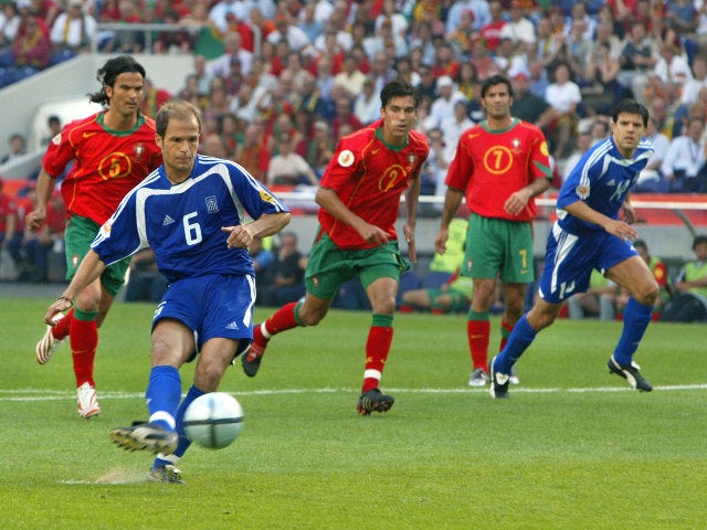 Greece's midfielder Angelis Basinas (foreground) kicks the ball to score 12 June 2004 at Dragao stadium in Porto during the Euro 2004 group A football match between Portugal and Greece at the European Nations championship in Portugal.