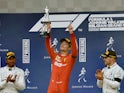 Charles Leclerc celebrates with a trophy on the podium after winning the race as he applauded by second placed Mercedes' Lewis Hamilton and third placed Mercedes' Valtteri Bottas on September 1, 2019