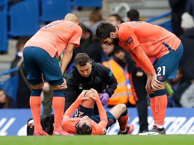 Everton's Andre Gomes and Richarlison look on as Bernard receives medical attention after sustaining an injury in March 2020
