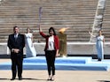 Former Japanese swimmer Imoto Naoko holds the Olympic torch next to Greek Sports Minister and HOC President Spyros Capralos during the olympic flame handover ceremony for the 2020 Tokyo Summer Olympics. The ceremony is being held behind closed doors as th