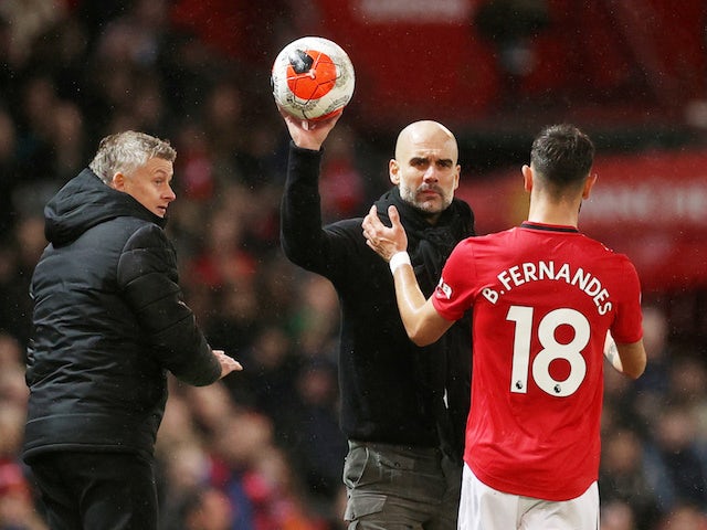 Manchester City manager Pep Guardiola hands the ball to Manchester United's Bruno Fernandes as Manchester United manager Ole Gunnar Solskjaer looks on in March 2020