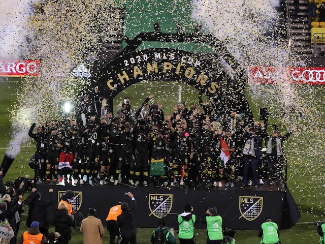 Columbus Crew players celebrate on stage with the MLS Cup championship trophy after defeating the Seattle Sounders in the 2020 MLS Cup Final at MAPFRE Stadium in December 2020