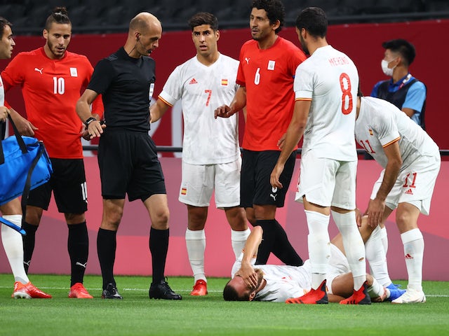 Oscar Mingueza de España reacciona después de sufrir una lesión cuando Ahmed Hegazy de Egipto reacciona junto al árbitro Adham Makhadmeh el 22 de julio de 2021