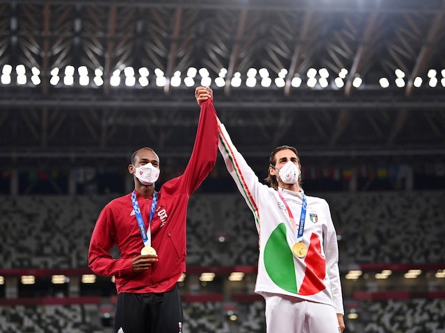 Gold medallists, Gianmarco Tamberi of Italy and Mutaz Essa Barshim of Qatar wearing protective face masks celebrate on the podium in August 2021