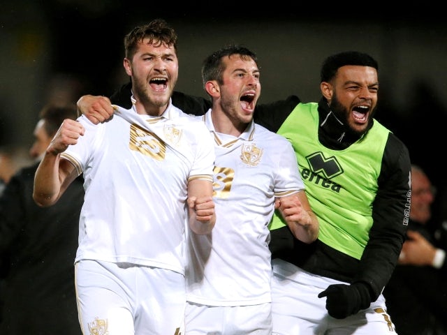 Port Vale's Brad Walker, Ben Garrity and Ryan Johnson celebrate after their FA Cup second round win against Burton Albion on December 4, 2021