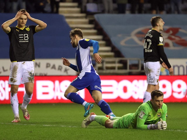 Wigan Athletic's Callum Lang celebrates scoring their first goal as Oxford United's Jack Stephens and teammates react on February 1, 2022