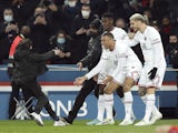 Paris Saint-Germain's (PSG) Kylian Mbappe celebrates scoring their first goal with teammates and a pitch invader on February 11, 2022