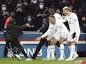 Paris Saint-Germain's (PSG) Kylian Mbappe celebrates scoring their first goal with teammates and a pitch invader on February 11, 2022